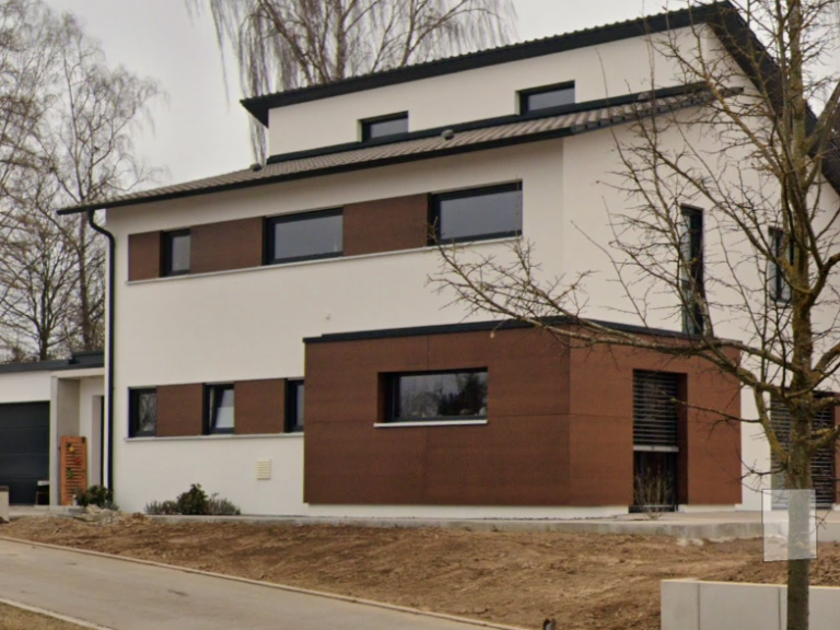 Modernes zweigeschossiges Haus mit Holzverkleidung und großen Fenstern.