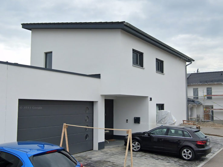 Modernes, zweigeschossiges Wohnhaus in hellen Farben mit Garagetür und Parkplatz.