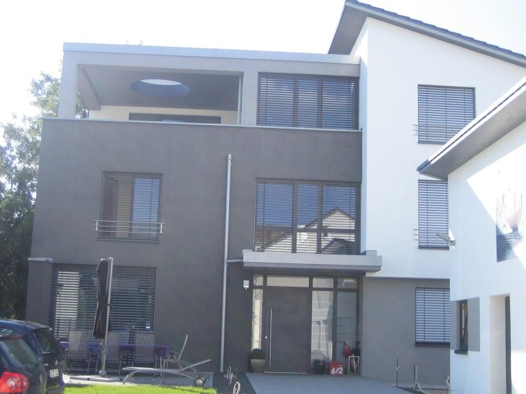 Moderne zweigeschossige Gebäude mit großflächigen Fenstern und einem flachen Dach.