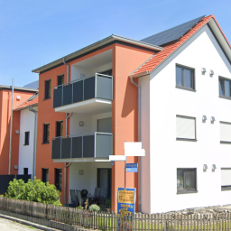 Moderne Wohngebäude mit zwei Balkonen und einem begrünten Außenbereich.