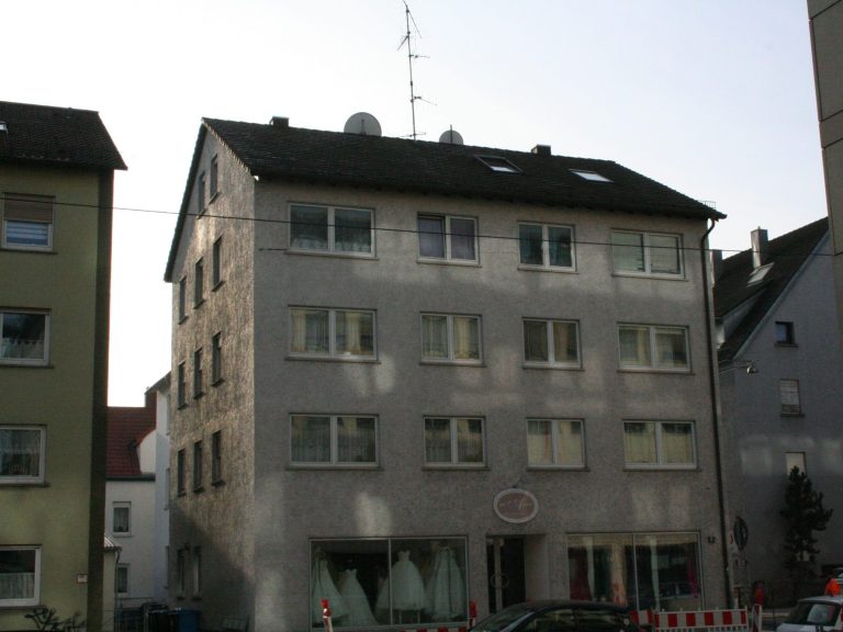 Mehrstöckiges Wohngebäude mit vielen Fenstern und Antenne auf dem Dach.