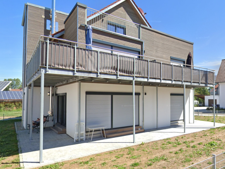 Modernes Wohnhaus mit Hausbalkon und Rollläden im Erdgeschoss.